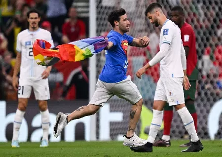 A man carrying a rainbow flag invades the field during a FIFA World Cup game